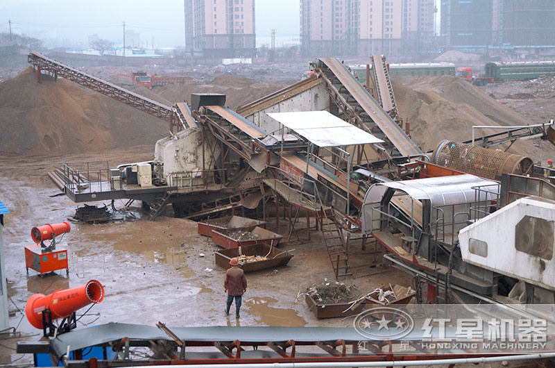 環(huán)保破碎站設(shè)備正在處理建筑垃圾，配置霧炮機除塵